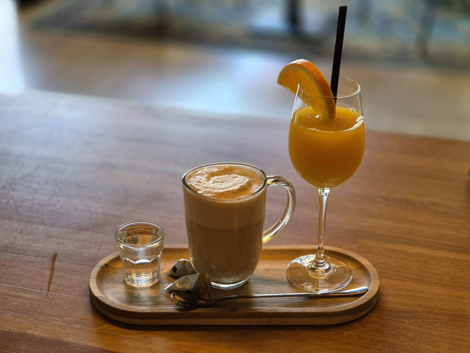 Latte a pomerančový džus na dřevěném podnosu